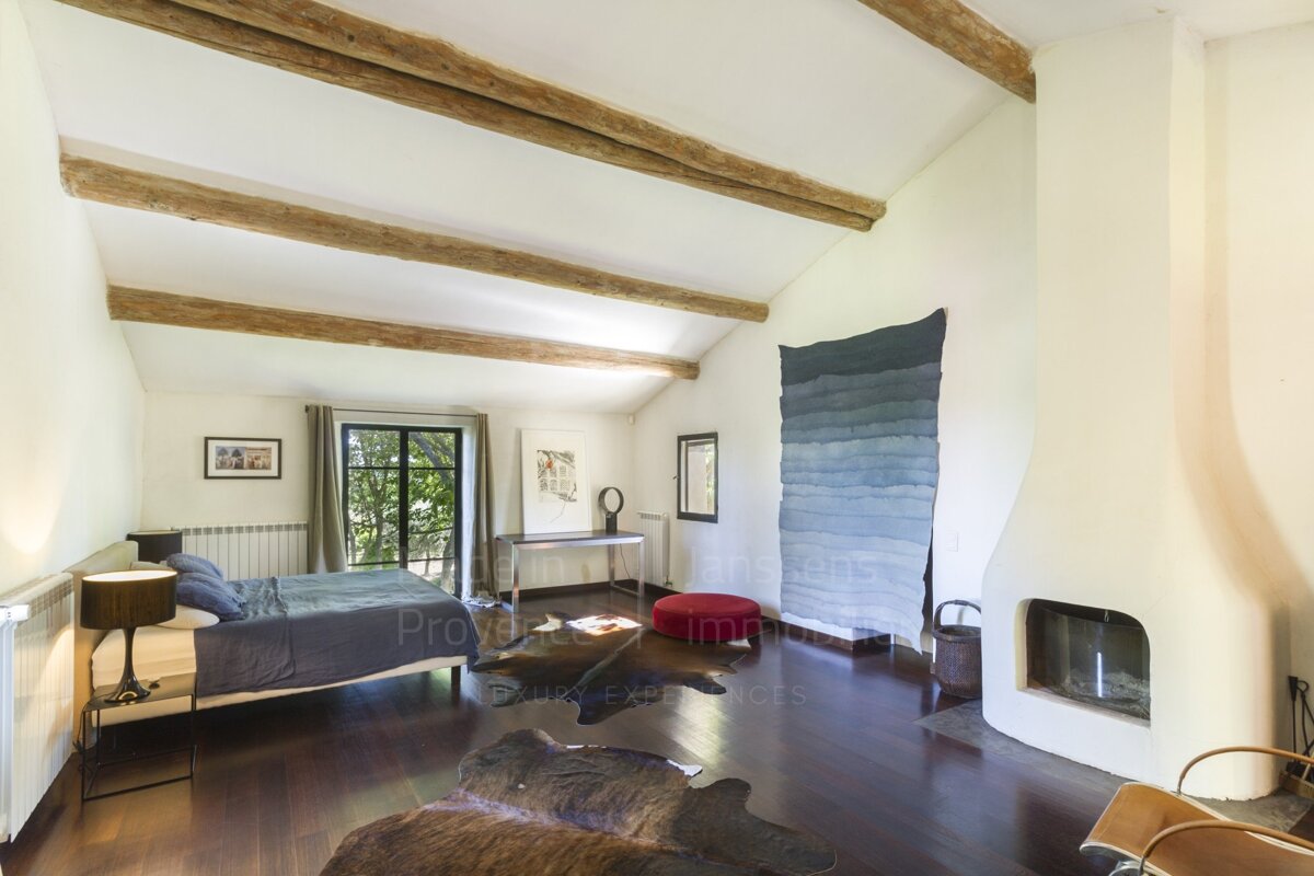 A bedroom with a fireplace and a rug that says provence immobilier
