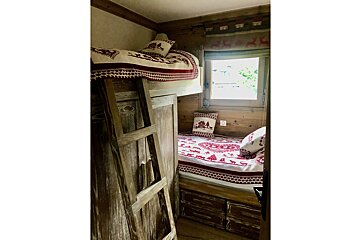 A bunk bed with red and white blankets and pillows