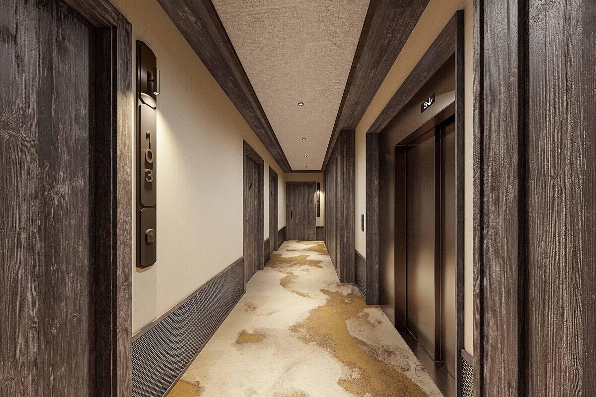 A modern hotel hallway with dark wood doors, trim, and wall panels. It features a beige carpet with abstract gold patterns and an elevator. Room 103 is visible.