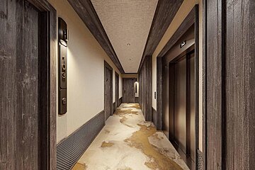 A modern hotel hallway with dark wood doors, trim, and wall panels. It features a beige carpet with abstract gold patterns and an elevator. Room 103 is visible.