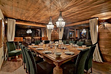 A dining room with a long table and green chairs