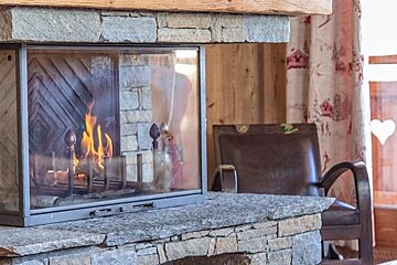 A fireplace in a living room with a chair in the background