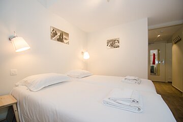 A bedroom with two beds and two pictures on the wall