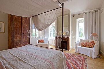 A bedroom with a canopy bed and chairs and the words maison provence immobilier on the wall