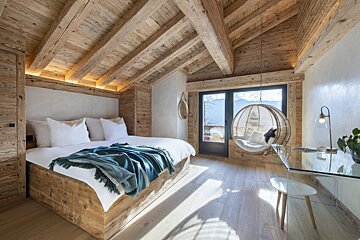 A bedroom with a large bed and a hanging chair