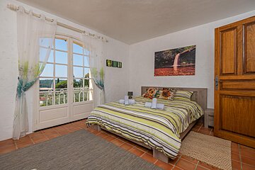 A bedroom with a painting on the wall above the bed