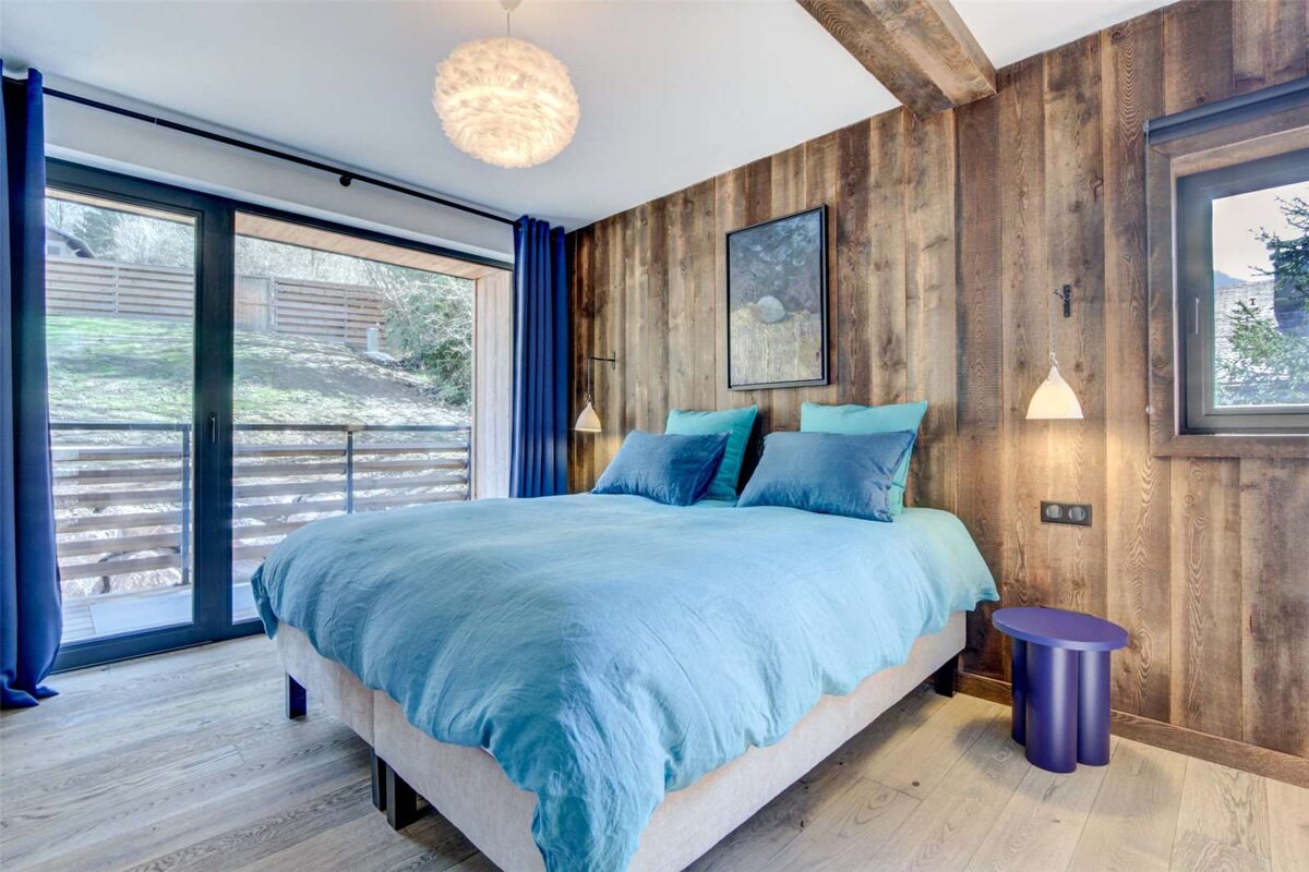 A bedroom with a blue bed and a blue stool