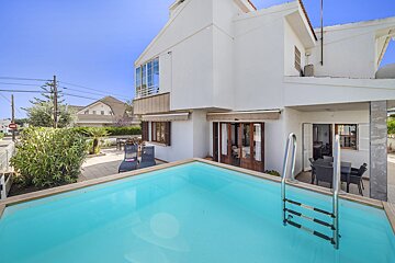 A white house with a swimming pool in front of it