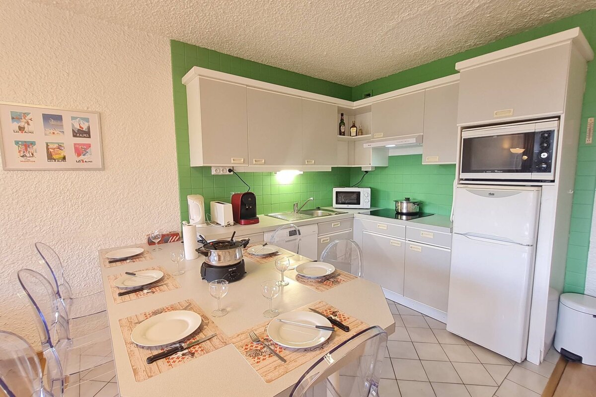 A small kitchen with white cabinets and green walls
