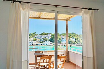 A sliding glass door leading to a balcony with a table and chairs