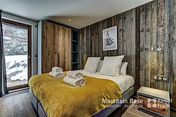 A bedroom with a bed and a picture on the wall that says mountain base