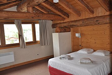 A bedroom with wooden beams and a bed