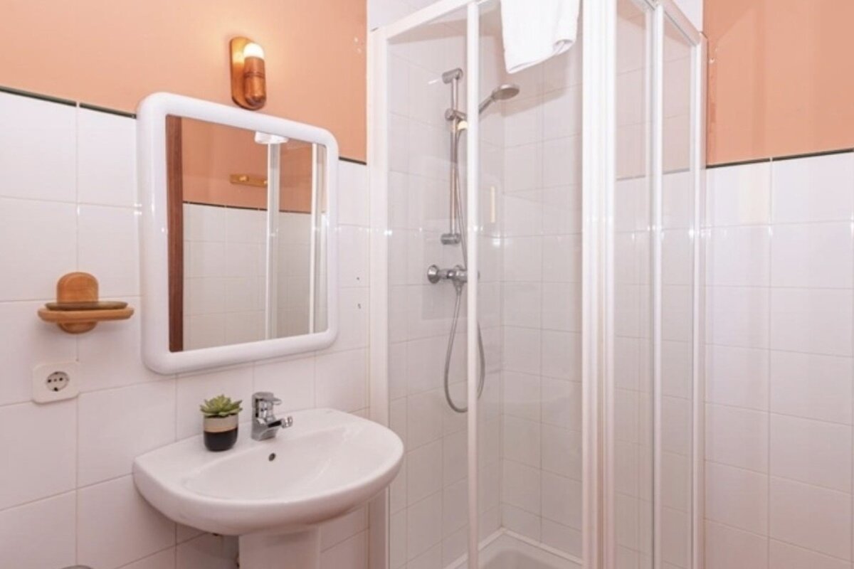 A bathroom with a sink a mirror and a shower