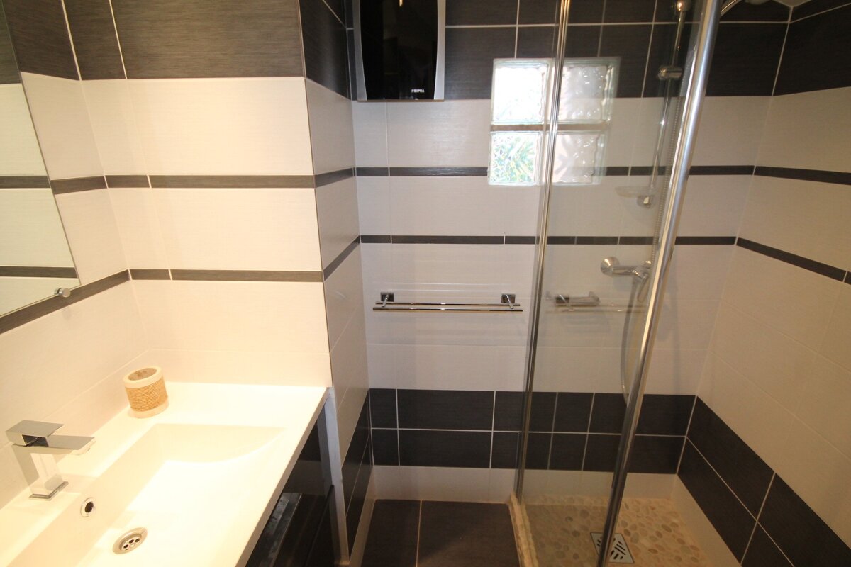 A bathroom with black and white tiles and a walk in shower