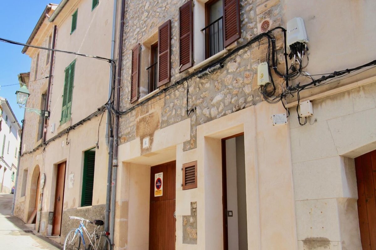 A bicycle is parked in front of a building with a no parking sign