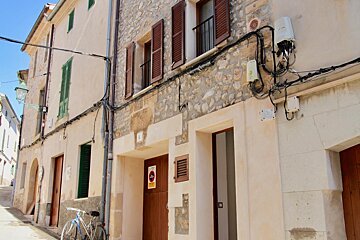 A bicycle is parked in front of a building with a no parking sign