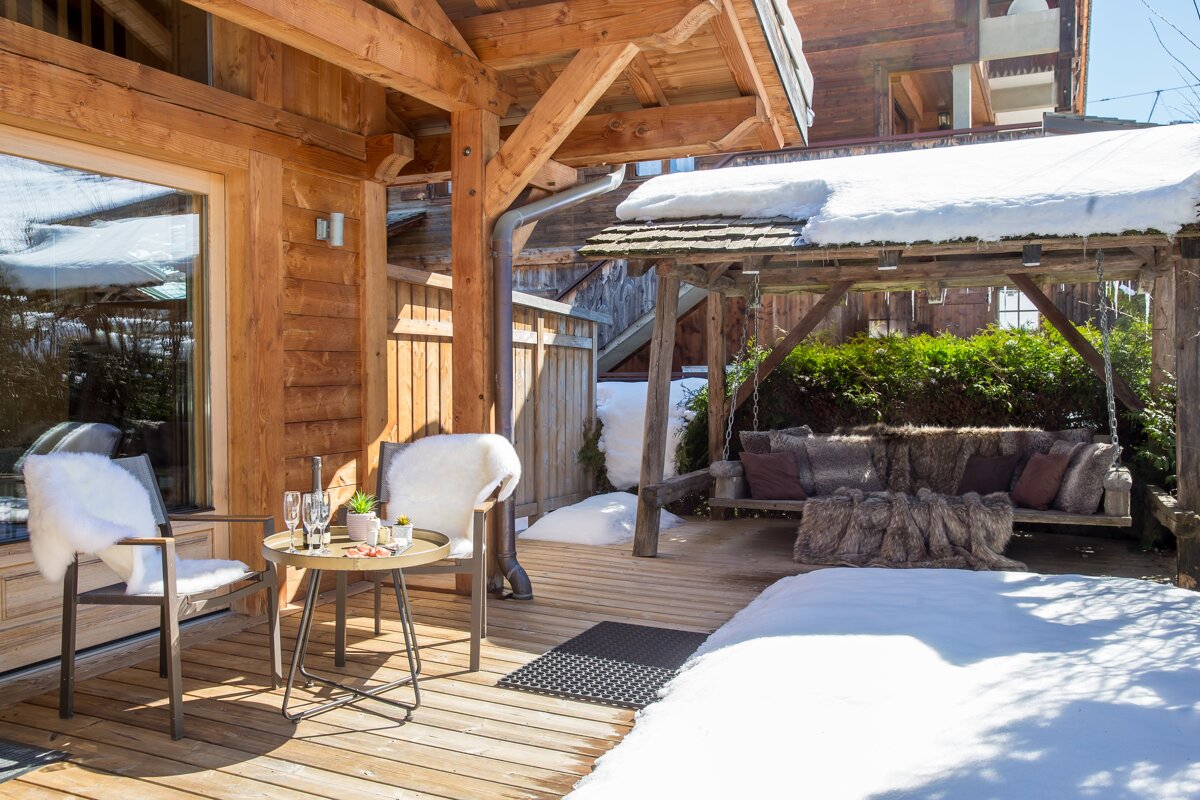 A wooden deck with a table and chairs and a swing
