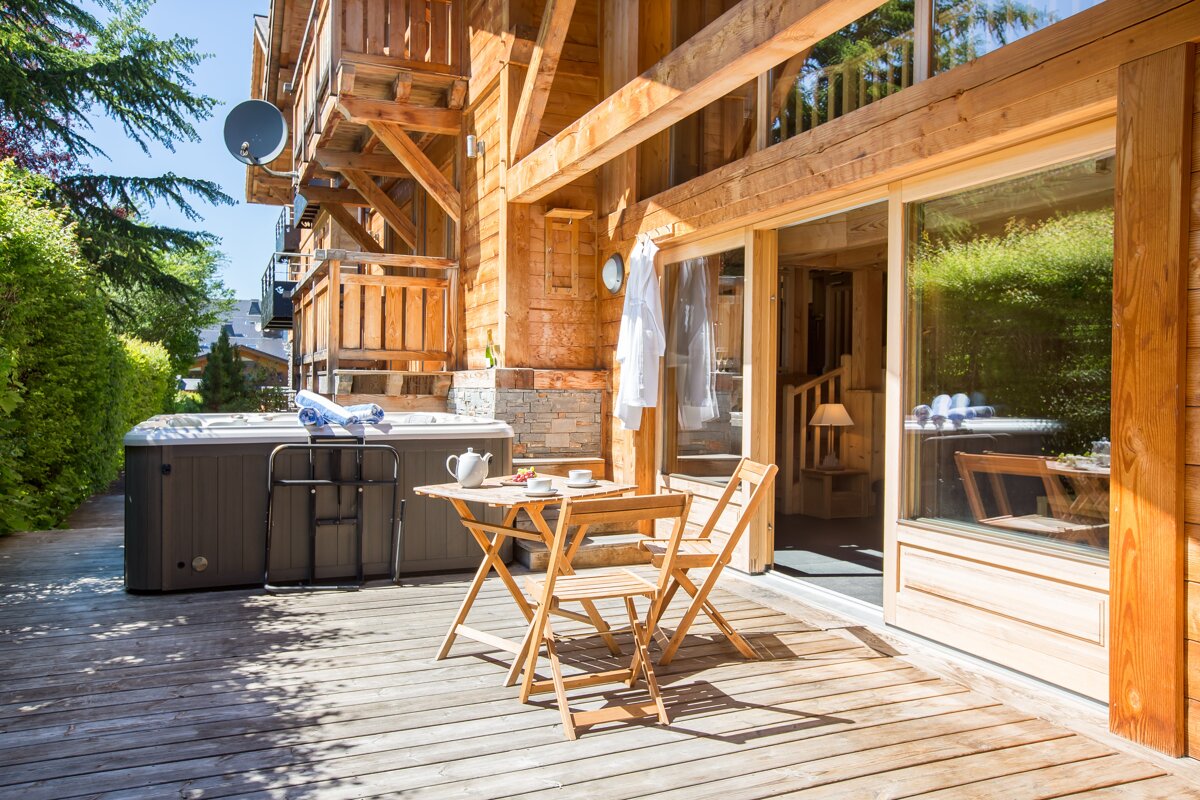 A wooden deck with a table and chairs and a hot tub