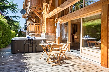A wooden deck with a table and chairs and a hot tub