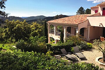 A house with a view of mountains is surrounded by trees
