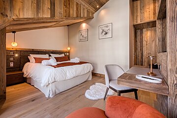 A bedroom with a large bed and a desk