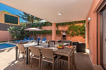 A patio with a table and chairs and a bottle of wine on it
