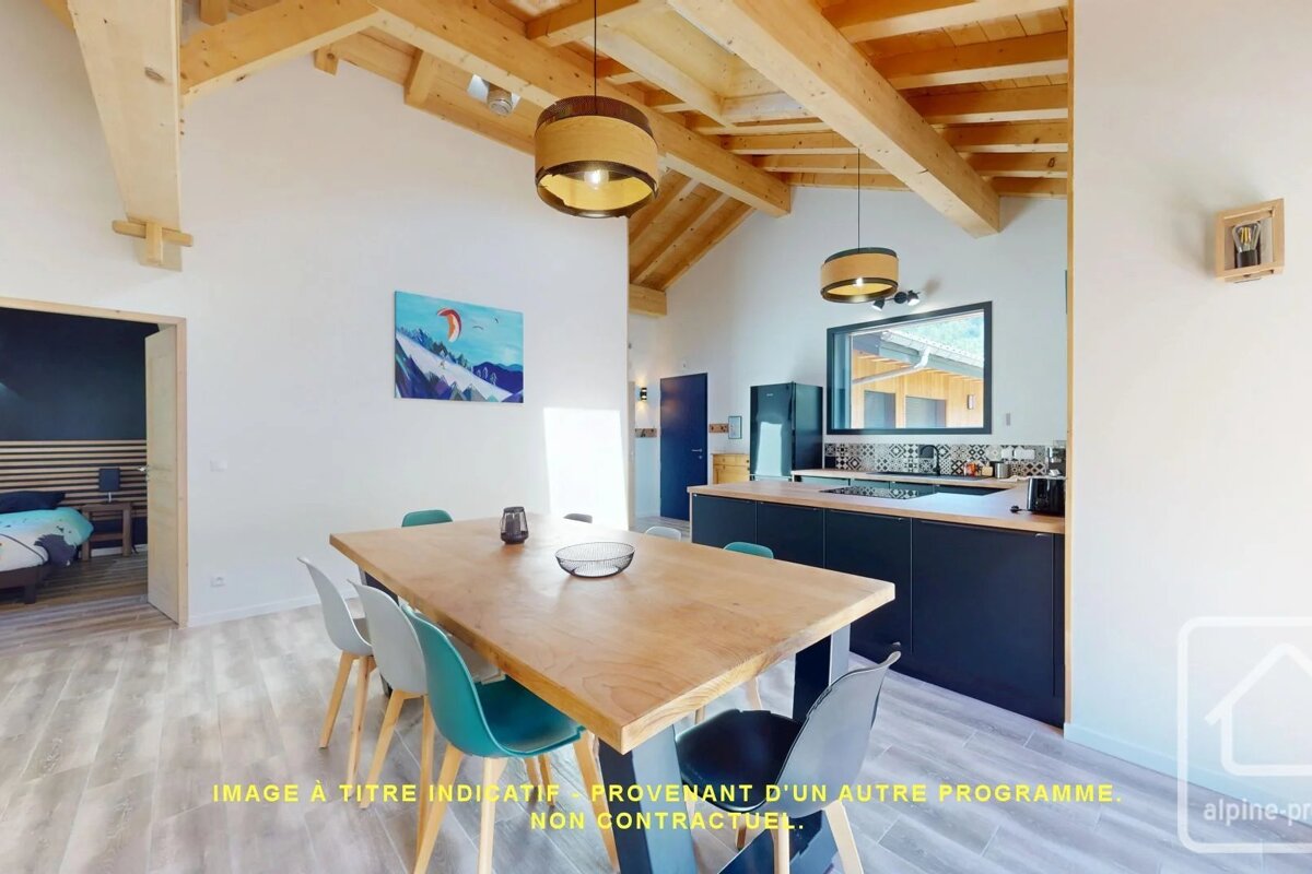 Modern open-plan kitchen and dining area featuring a wooden table with colorful chairs under exposed wooden ceiling beams.
