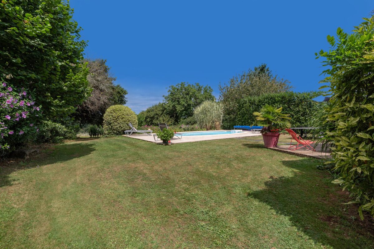 A large lawn with a swimming pool in the background