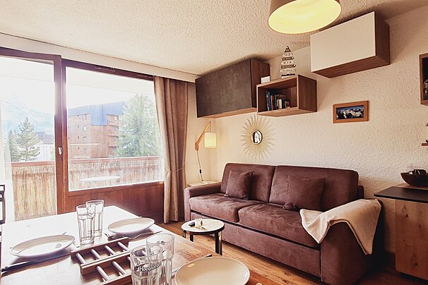 A living room with a couch and a shelf with a sailboat on it