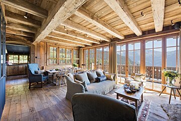 A living room with a couch and chairs and a view of the mountains