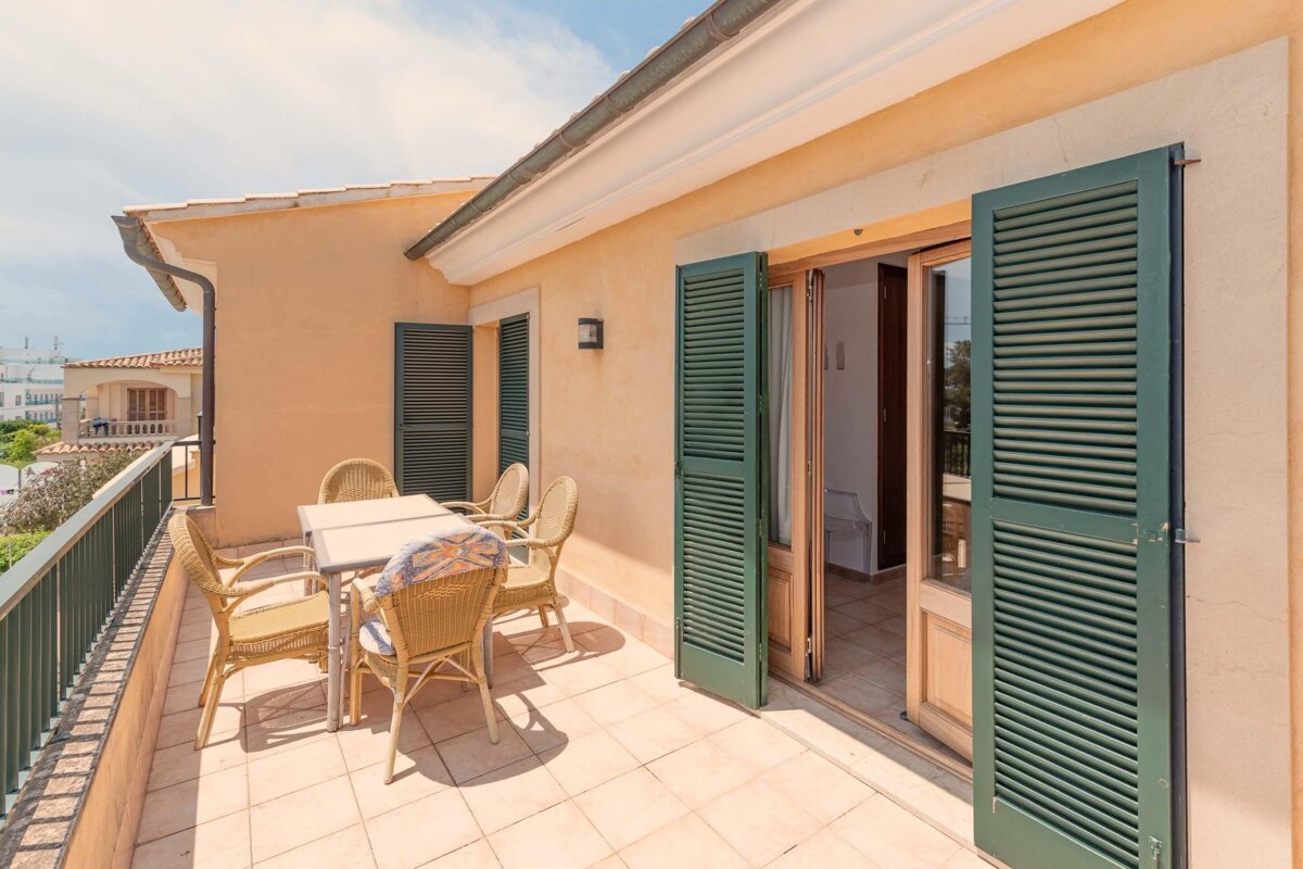 A balcony with a table and chairs and green shutters