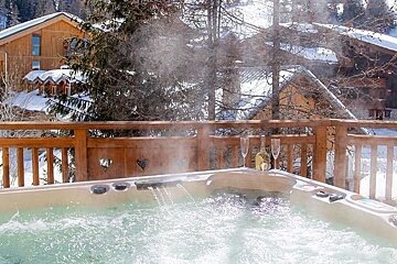 A hot tub with steam coming out of it on a snowy deck