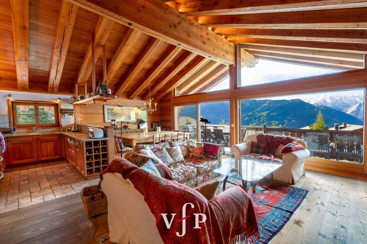 Cozy alpine chalet interior with rustic wooden beams and large windows overlooking scenic mountain views.