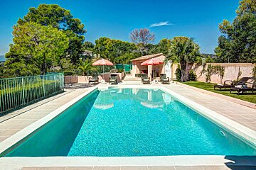 A large swimming pool is surrounded by chairs and umbrellas