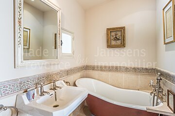 A bathroom with a bathtub and a sink and the word janssens on the wall