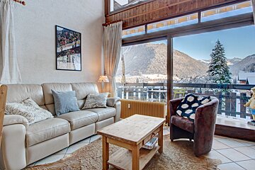 A living room with a couch and a chair with a view of the mountains