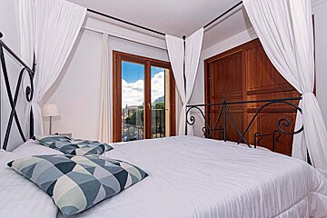 A bedroom with a canopy bed and a balcony