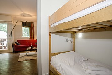 A bedroom with a bunk bed and a red couch