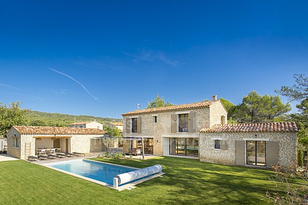 A large stone house with a swimming pool in front of it