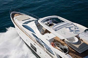 A man stands on the deck of a white yacht with the letters e on the side