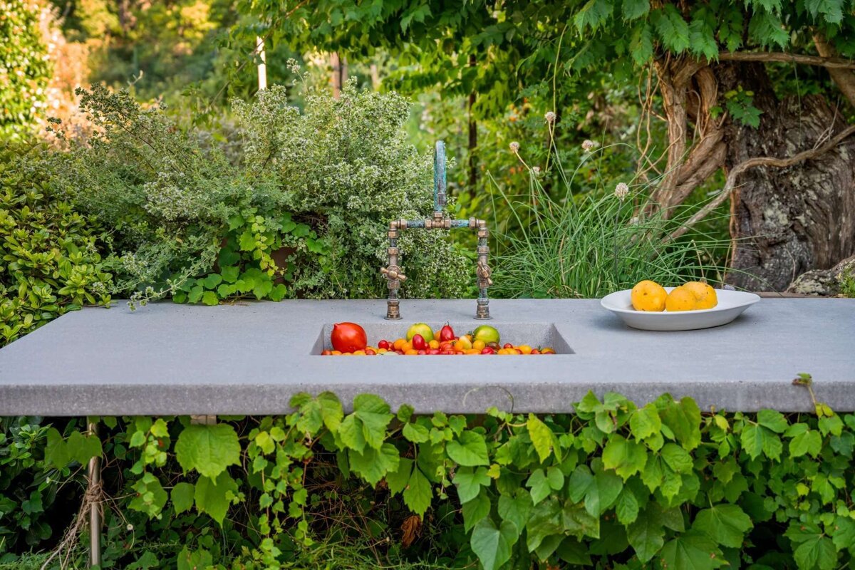 A bowl of lemons sits next to a sink filled with fruit