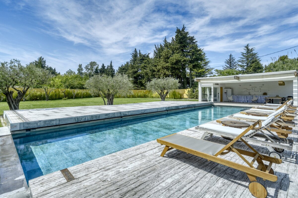 A large swimming pool surrounded by lawn chairs and trees