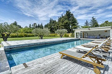 A large swimming pool surrounded by lawn chairs and trees
