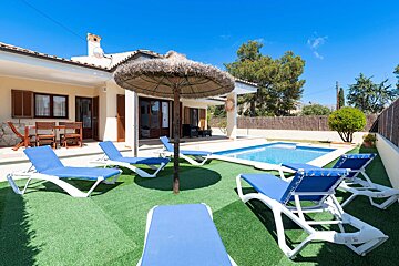 A house with a pool and lawn chairs in front of it