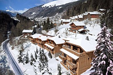 A snowy landscape with a few houses and trees
