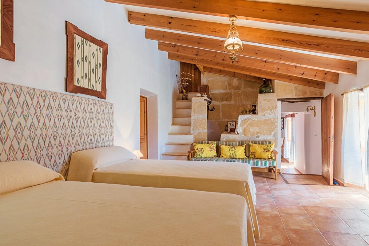 A bedroom with two beds and a couch with yellow pillows