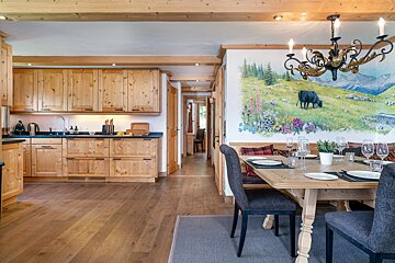 A kitchen and dining room with a painting of a cow on the wall