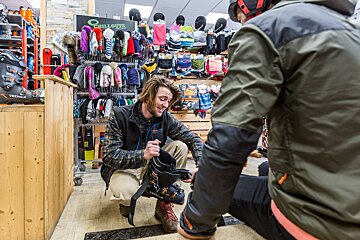 A man is helping a woman put on a pair of tech boots