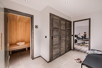 A man is riding an exercise bike in a gym next to a sauna