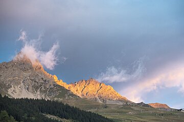 A mountain with a cloudy sky in the background